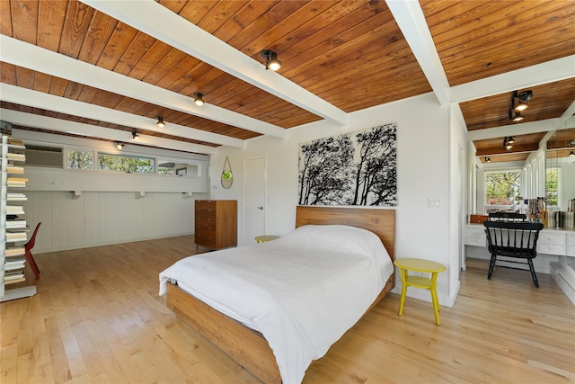 bedroom featuring rail lighting, beam ceiling, and light wood-style floors