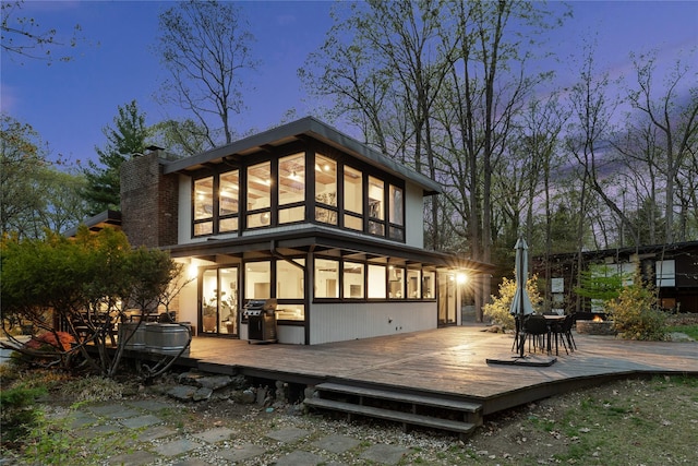 back of house with a deck and a chimney