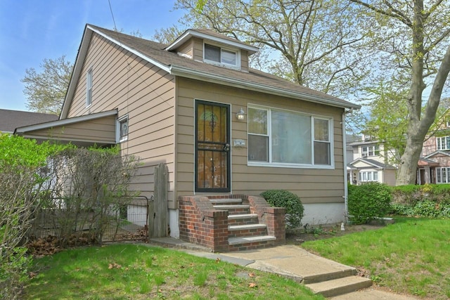 bungalow-style house with a front lawn and fence