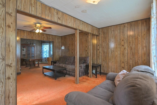 living area with carpet flooring, a ceiling fan, and wooden walls