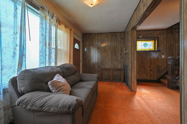 living area featuring wooden walls and light carpet