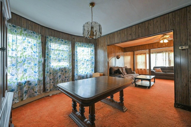 recreation room with carpet, a chandelier, a healthy amount of sunlight, and wooden walls