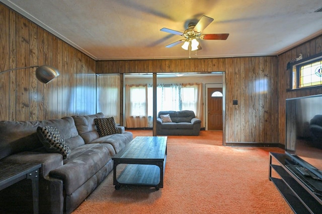 carpeted living area featuring wooden walls and a ceiling fan