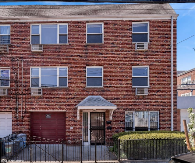 multi unit property featuring a fenced front yard, an attached garage, driveway, and brick siding