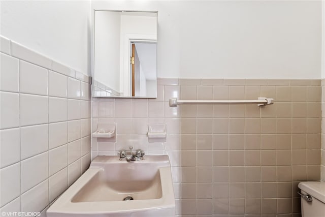 bathroom featuring a sink, tile walls, and toilet