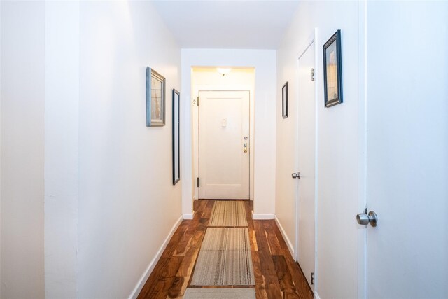 corridor featuring dark wood-style flooring and baseboards