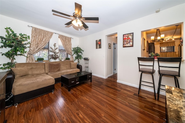 living area featuring baseboards, ceiling fan with notable chandelier, and wood finished floors