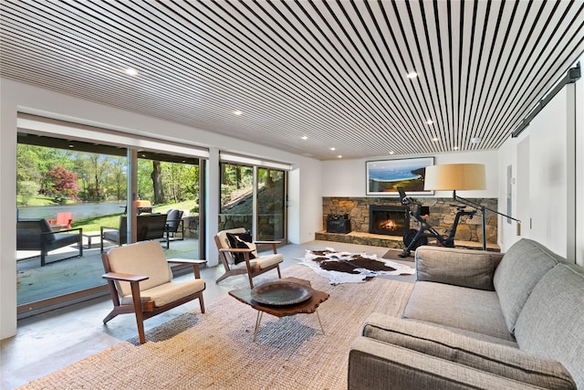 living room featuring concrete flooring, recessed lighting, a stone fireplace, and a healthy amount of sunlight