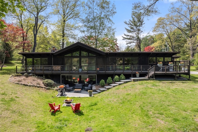 rear view of house with a wooden deck, a patio, a yard, and a fire pit