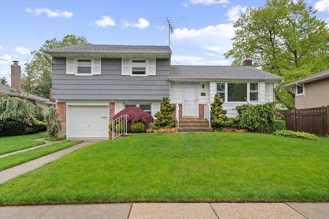 split level home with fence, brick siding, a garage, a front yard, and a chimney