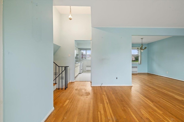 interior space with hardwood / wood-style floors, radiator heating unit, an inviting chandelier, and plenty of natural light