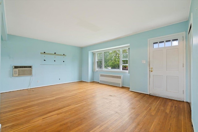 entrance foyer featuring radiator, hardwood / wood-style floors, a wall unit AC, and baseboards