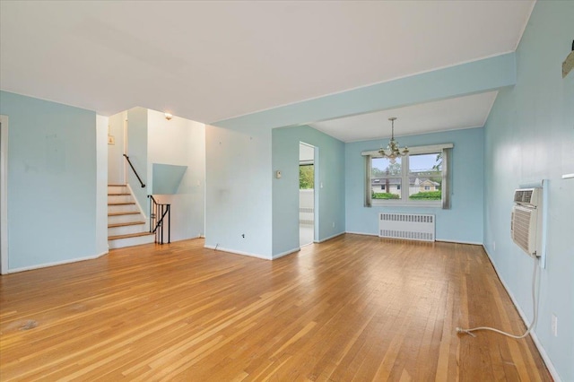 unfurnished living room with radiator, baseboards, stairway, a notable chandelier, and light wood-style floors