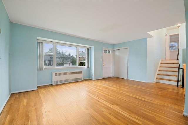 unfurnished bedroom featuring baseboards, a closet, radiator heating unit, and wood-type flooring
