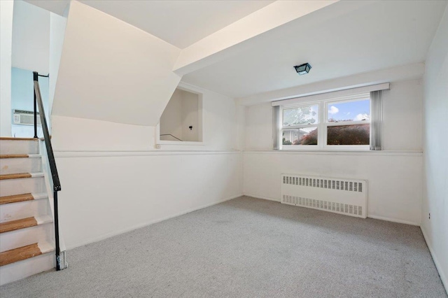 additional living space with stairway, carpet flooring, baseboards, and radiator heating unit