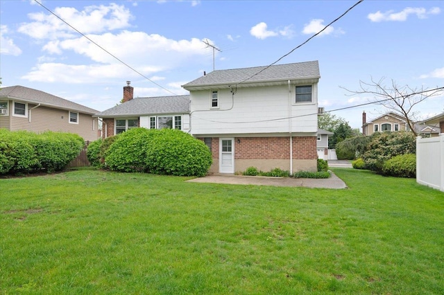 back of property with brick siding, fence, and a lawn
