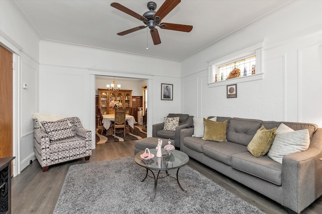 living area with wood finished floors, ceiling fan with notable chandelier, and a decorative wall