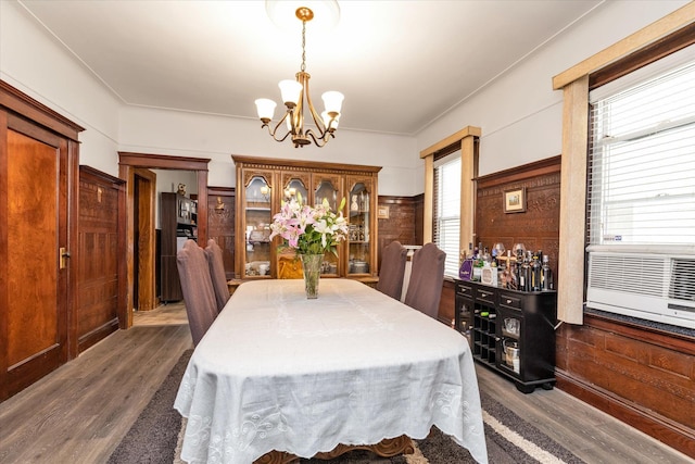 dining space featuring cooling unit, wood finished floors, and a chandelier