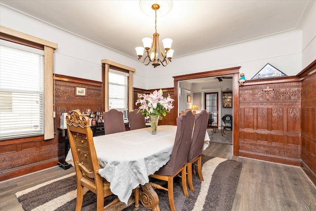 dining room featuring wooden walls, wood finished floors, and a notable chandelier