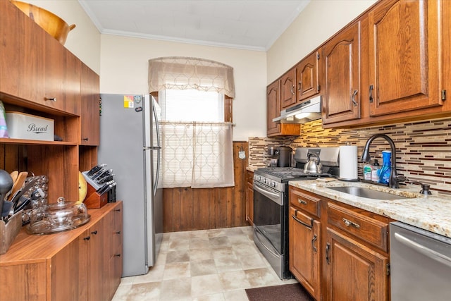 kitchen with brown cabinets, tasteful backsplash, a sink, stainless steel appliances, and under cabinet range hood