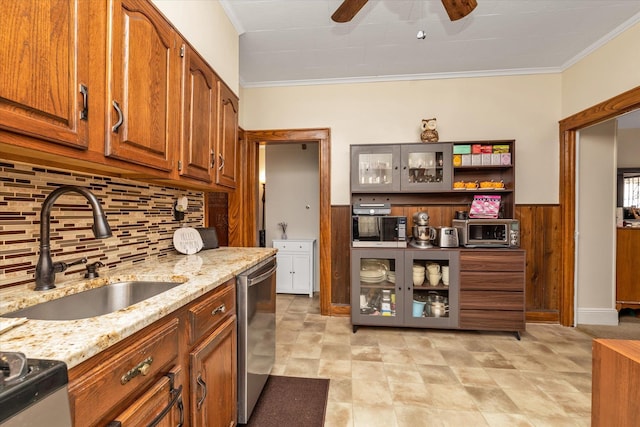 kitchen with a sink, ceiling fan, tasteful backsplash, light stone counters, and ornamental molding