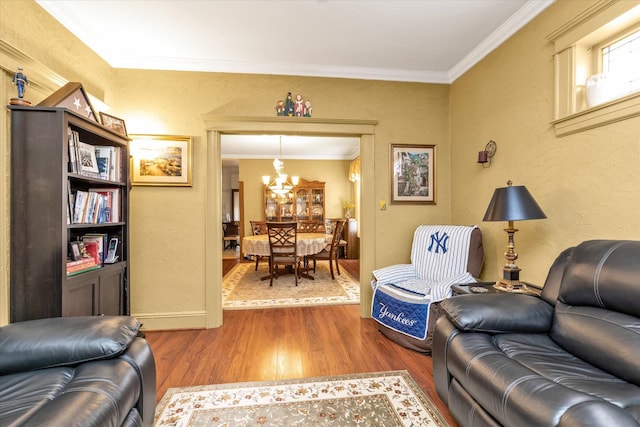 living area with a chandelier, wood finished floors, ornamental molding, and a textured wall