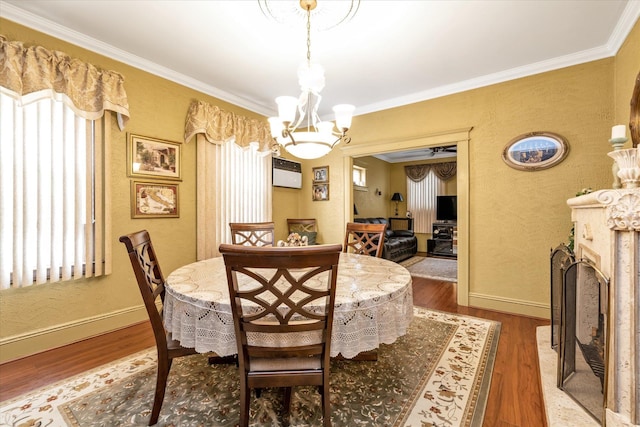 dining area featuring wood finished floors, ornamental molding, and a textured wall