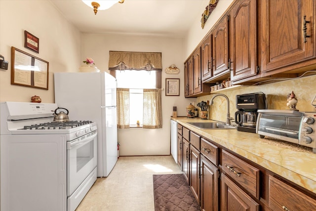 kitchen with a sink, white range with gas stovetop, brown cabinetry, light countertops, and a toaster