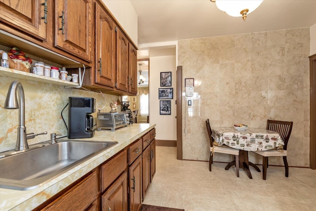 kitchen featuring a sink, open shelves, brown cabinetry, and light countertops