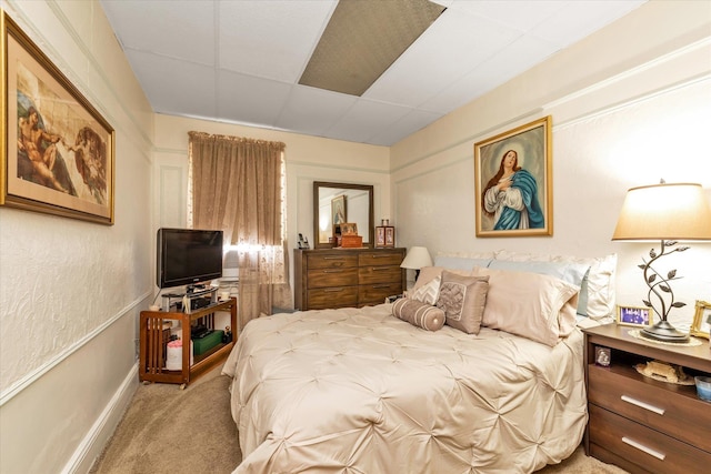 bedroom with a drop ceiling, carpet flooring, and baseboards