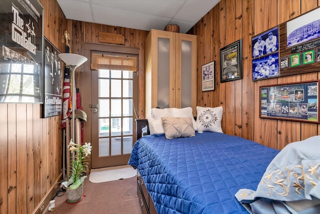 carpeted bedroom featuring wooden walls