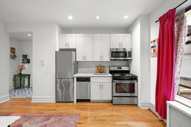 kitchen with light wood-style floors, baseboards, stainless steel appliances, and a sink