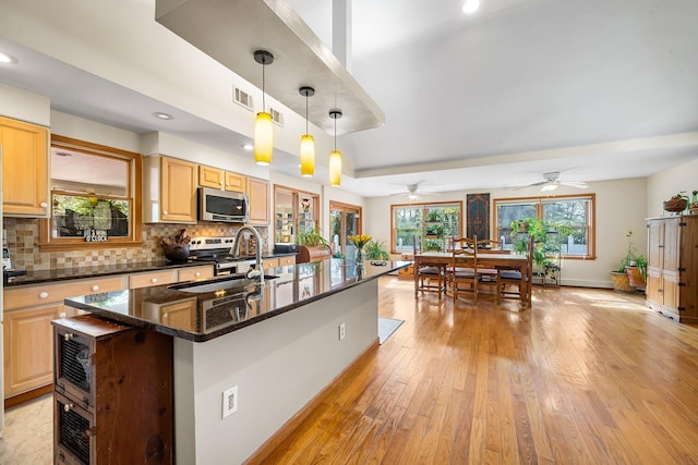 kitchen with plenty of natural light, a sink, stainless steel microwave, and tasteful backsplash