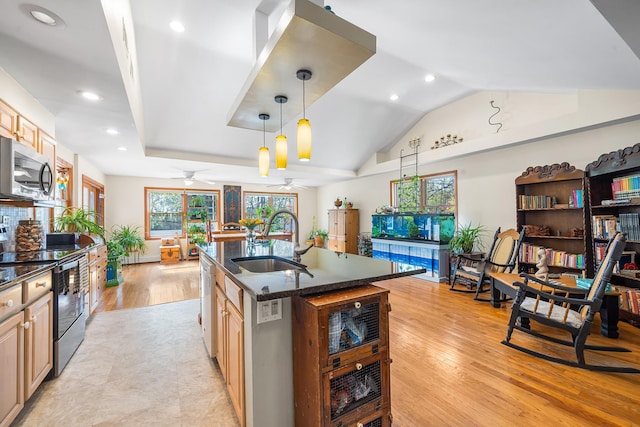 kitchen with a ceiling fan, a sink, dark stone countertops, vaulted ceiling, and stainless steel appliances