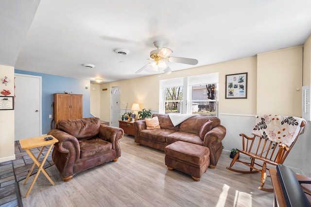 living room featuring baseboards, a ceiling fan, and light wood-style flooring