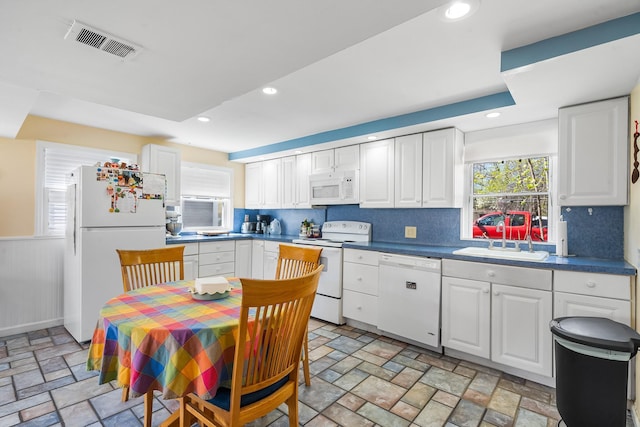 kitchen with visible vents, stone tile floors, white appliances, white cabinetry, and a sink