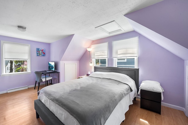 bedroom with a textured ceiling, attic access, baseboards, a baseboard heating unit, and vaulted ceiling