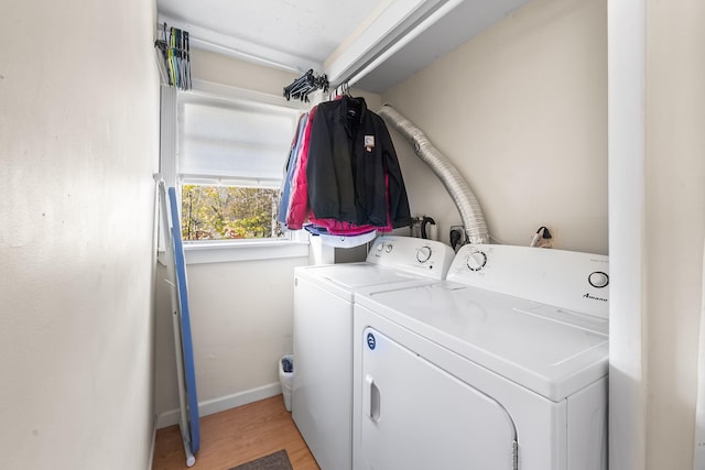 laundry room featuring washing machine and clothes dryer, baseboards, laundry area, and light wood-type flooring