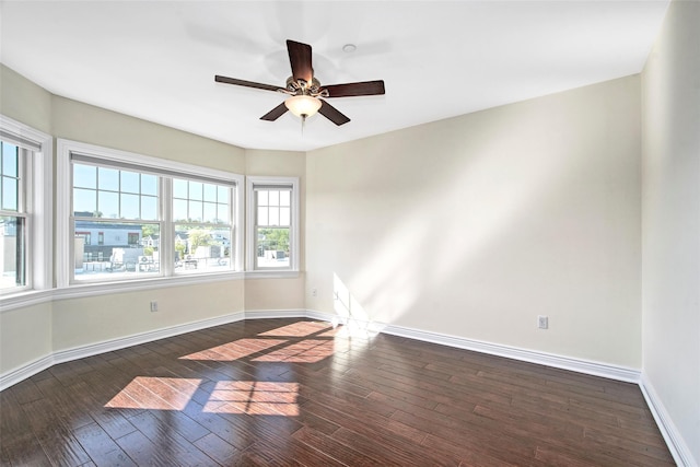 empty room featuring baseboards, dark wood-style flooring, and ceiling fan
