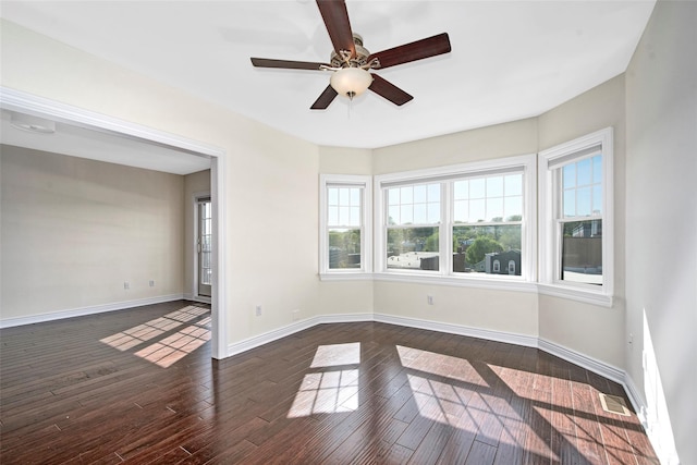 empty room with baseboards, ceiling fan, and dark wood-style floors