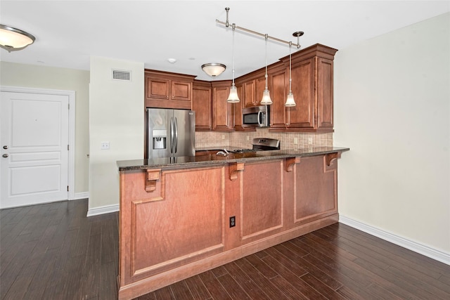 kitchen with visible vents, brown cabinetry, baseboards, dark stone countertops, and appliances with stainless steel finishes