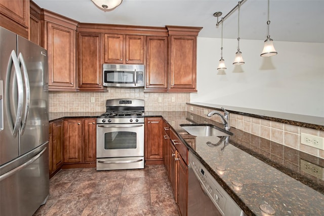 kitchen featuring decorative backsplash, brown cabinetry, appliances with stainless steel finishes, a sink, and dark stone counters