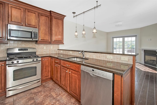 kitchen with brown cabinets, stainless steel appliances, a sink, and a peninsula
