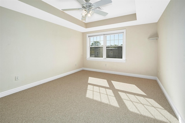 carpeted spare room with a ceiling fan, baseboards, visible vents, and a raised ceiling