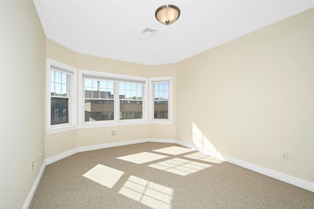 carpeted empty room with visible vents, baseboards, and a healthy amount of sunlight