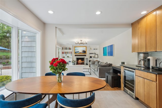 dining room featuring beverage cooler, a chandelier, a warm lit fireplace, light tile patterned floors, and recessed lighting