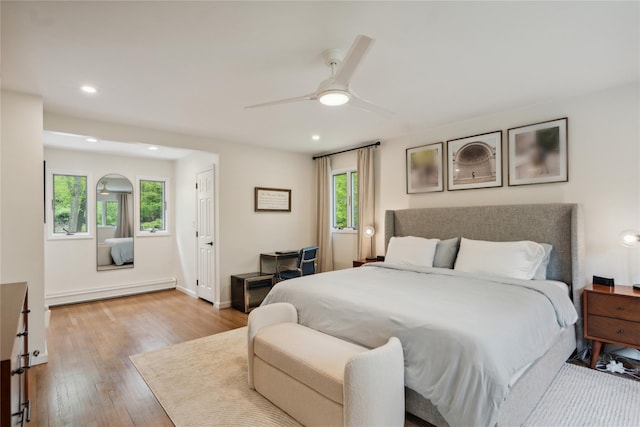 bedroom with wood finished floors, baseboards, baseboard heating, ceiling fan, and recessed lighting