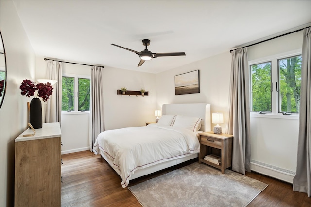 bedroom featuring baseboards, multiple windows, a baseboard radiator, and dark wood-style flooring