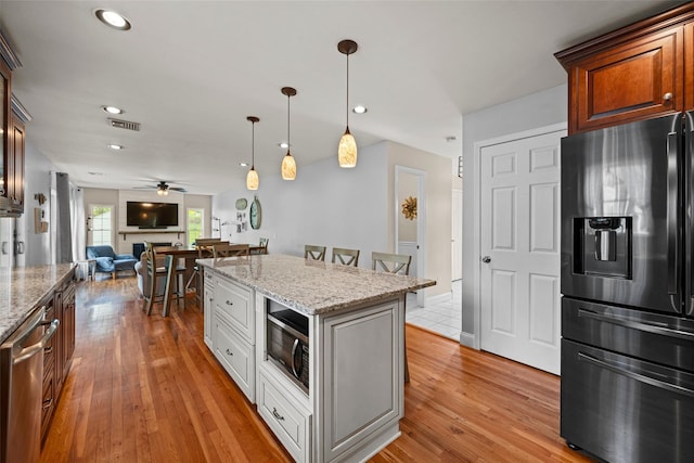kitchen featuring appliances with stainless steel finishes, light wood-style flooring, a ceiling fan, open floor plan, and visible vents
