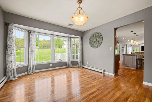 spare room featuring visible vents, baseboards, wood finished floors, and baseboard heating